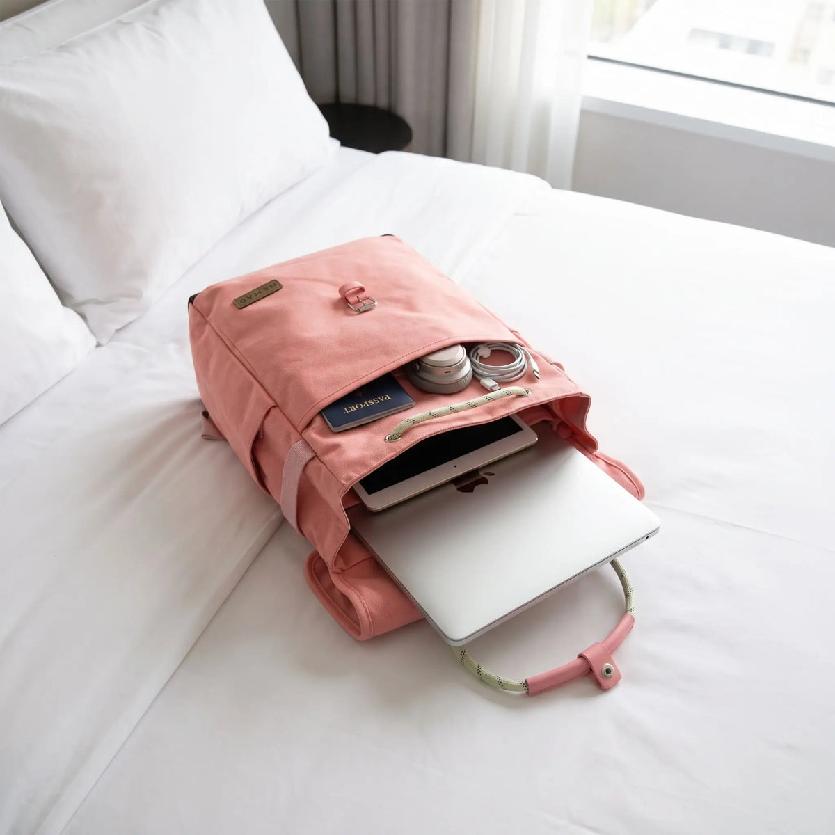 sac a dos ordinateur portable rose organise sur lit d'hôtel